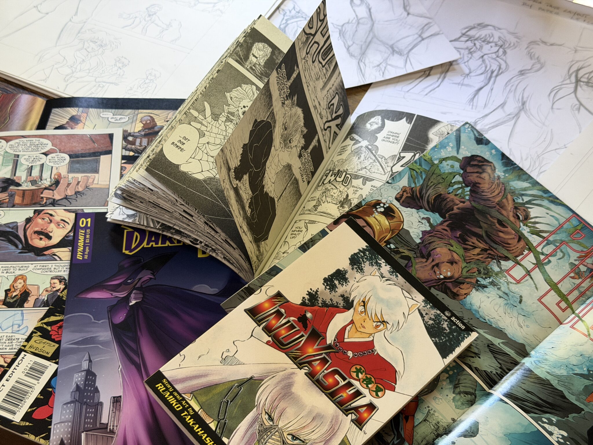 Comic Books, manga, graphic novels open on a table with pages flipping.